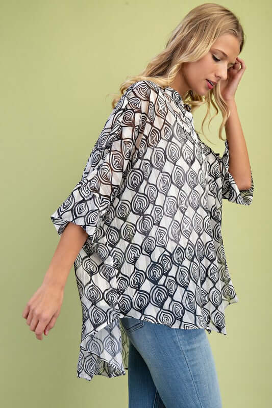 Loose fit sheer lurex button down top with hi-low hem in black and white pattern, styled with denim.